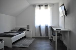 um quarto com uma cama, uma secretária e uma janela em B Home SLEEP & WORK em Burgrieden