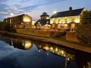un edificio iluminado junto a un río por la noche en Boat & Horses Inn, en Oldham