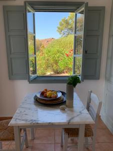uma mesa com um prato de frutas em frente a uma janela em PATMOS Confidential em Patmos