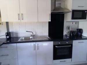 eine Küche mit weißen Schränken und einem Waschbecken in der Unterkunft Ben Breen House Apartment in Crockaunroe