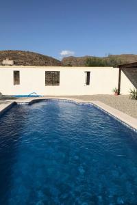 a swimming pool with blue water in front of a building at Bella Vista Rural Retreat in Arboleas