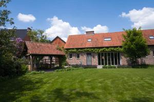 une grande maison en briques avec une cour verdoyante dans l'établissement Glabbeek-hoeve, à Geetbets