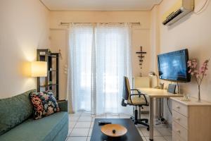 a living room with a couch and a desk and a television at Flat in excellent location with private parking in Athens