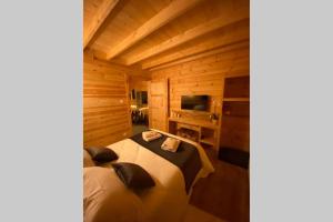um quarto com uma cama num chalé de madeira em Chalet L'Élégance - SPA - Serviettes - Peignoirs - Lits faits - Ménage inclus em Rochesson