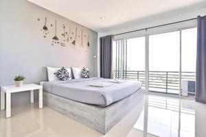 a white bedroom with a bed and a balcony at Rest Point Sampran in Nakhon Pathom