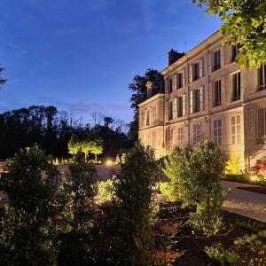 un edificio con arbustos delante de él por la noche en Château du Rollin Orléans - La Chapelle St Mesmin, en La Chapelle-Saint-Mesmin