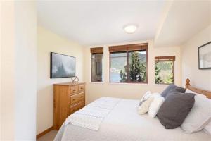 a bedroom with a white bed and two windows at Beautiful 2 bedroom overlooking Whistler's Green Lake and Mountains! in Whistler