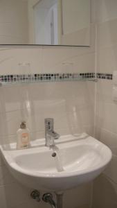 lavabo blanco en el baño con espejo en Appartements CHE, en Viena