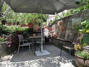 a patio with a table and chairs and an umbrella at Casa do pescador in Machico