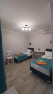 ein Zimmer mit 3 Betten und einem Stuhl darin in der Unterkunft Katerina Guest House in Anapa