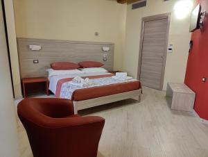 a hotel room with two beds and a chair at Dimora Del Corso in Rotonda