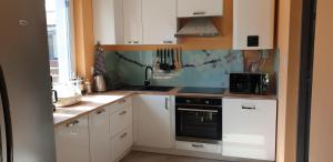 a kitchen with white cabinets and a black appliance at Mazury domek całoroczny przy lesie, jezioro in Pelnik