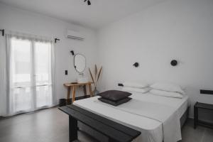biała sypialnia z dużym łóżkiem i lustrem w obiekcie Chris&C Apartments w mieście Agia Galini