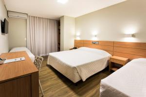 a hotel room with two beds and a desk at Tropikalya Gold Hotel in Balneário Camboriú +88 photos