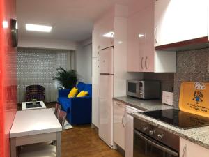 eine Küche mit weißen Schränken und einer blauen Couch in der Unterkunft APARTAMENTO MEXICO 6 (VIGO CENTRO) in Vigo + 7 Fotos