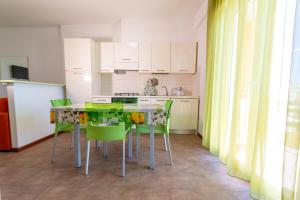 a kitchen with a table and green chairs at Residence Palazzo Sayonara in Tortoreto Lido