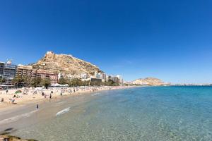 a beach with a bunch of people in the water at POSTIGUET BEACH in Alicante