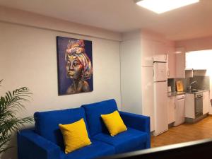 eine blaue Couch mit zwei gelben Kissen in einem Wohnzimmer in der Unterkunft APARTAMENTO MEXICO 6 (VIGO CENTRO) in Vigo