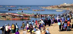 a group of people standing on a beach with boats at Keur Karim sarr in Mbour