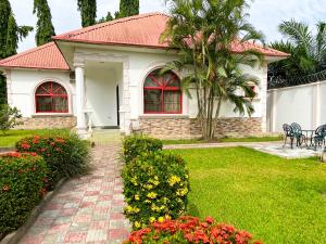 uma casa branca com um telhado vermelho e algumas flores em 2 Bedroom Bungalow in Alalubosa GRA em Ibadan