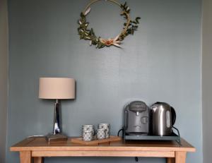 uma mesa com comodidades para preparar café e uma coroa de flores na parede em Les Rougemonts Eucalyptus em Champguyon