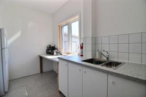 a white kitchen with a sink and a window at Chambres en ville La Tuque in La Tuque