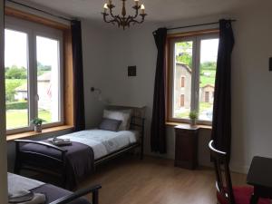 a bedroom with a bed and two large windows at 14-18 Meuse-Argonne in Montfaucon-dʼArgonne