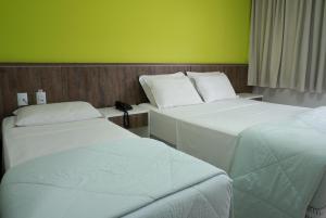 two beds in a room with a green wall at Pousada Quinta da Baleeira in Penha