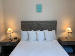 a bed with a white comforter and pillows at Coastal Inn and Suites in Long Beach