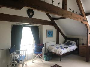 um quarto com uma cama e cadeiras num sótão em St Michaels House em Crediton