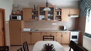 una cocina con armarios de madera y una mesa con comedor. en Keller Apartmanok, en Hajdúszoboszló
