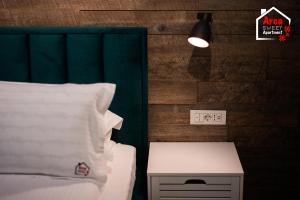 um quarto com uma cama, uma mesa de cabeceira e uma luz em Arca Sweet Apartment Ariniș em Gura Humorului