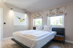 a bedroom with a large white bed with two windows at 2H Horizon Hotel in Kühlungsborn