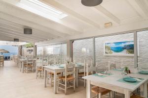 a dining room with tables and chairs and the ocean at Hotel Ristorante La Conchiglia in Cala Gonone