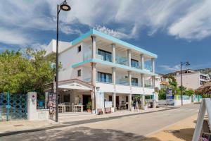 a white building with a blue roof on a street at Hotel Ristorante La Conchiglia in Cala Gonone