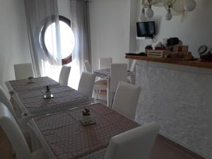 a dining room with a table and white chairs at Sweet Suite Margherita B&B in Margherita di Savoia