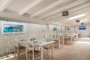 a dining room with white tables and chairs at Hotel Ristorante La Conchiglia in Cala Gonone