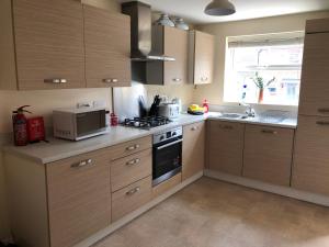 a kitchen with wooden cabinets and a stove top oven at Spring House - Staycation - Perfect for Contractors & Families - 2 Parking Spaces in Dudley