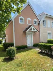 a pink house with a white door and a yard at Pepper Lake in Fort-Mahon-Plage