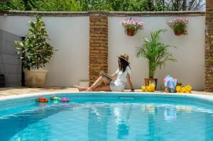 a woman sitting next to a swimming pool at La Casona de los Cinco Caños in Coca