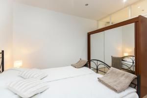 - une chambre avec un lit doté de draps blancs et d'un miroir dans l'établissement Apartman Lungo Mare, à Rabac