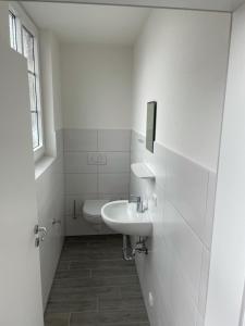 ein weißes Badezimmer mit Waschbecken und Toilette in der Unterkunft Fährstrasse 2 in Cuxhaven + 14 Fotos