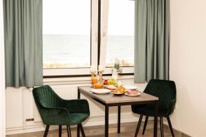 a table with a bowl of fruit and two chairs and a window at Direkt am Strand mit Meerblick perfekt für 2 Personen in Heiligenhafen