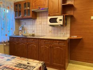 a kitchen with wooden cabinets and a microwave at Balaton Vendégház in Siófok