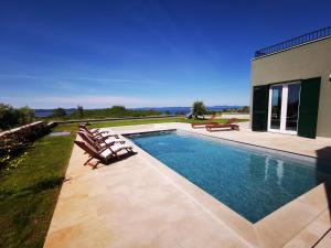 a swimming pool with lounge chairs and a house at Villa Gorana in Zadar