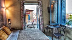 a bedroom with a bed and a balcony with a table and chairs at Porto Bello Nafplio in Nafplio