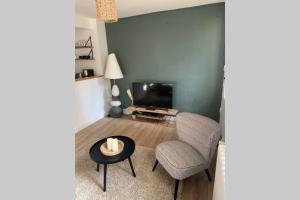 een woonkamer met een stoel, een tafel en een televisie bij L’escapade : maison centre-ville avec cour in Saumur