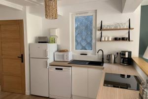 a kitchen with a white refrigerator and a window at L’escapade : maison centre-ville avec cour in Saumur