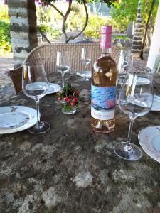 una bottiglia di vino seduta su un tavolo con bicchieri di Agriturismo Hibiscus a Ustica