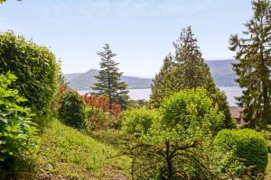 a garden with trees and a lake in the background at Magnificent chalet on the heights of Veyrier-du-Lac - Welkeys in Veyrier-du-Lac
